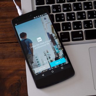 Mobile phone on top of laptop showing linkedin login page