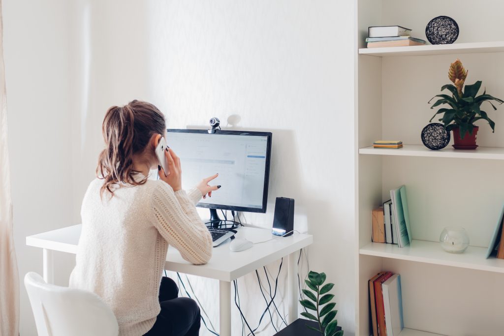 Work from home hr manager during coronavirus pandemic. Woman stays home talking on phone. Workspace of freelancer. Office interior with computer